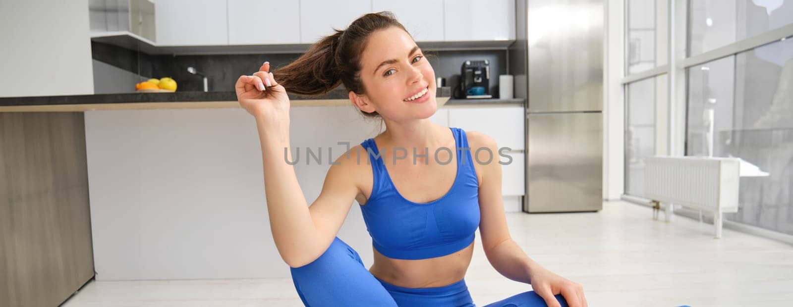 Yoga, welness and wellbeing. Young woman workout, does sport at home, female fitness instructor stretches before exercises on rubber mat in living room by Benzoix