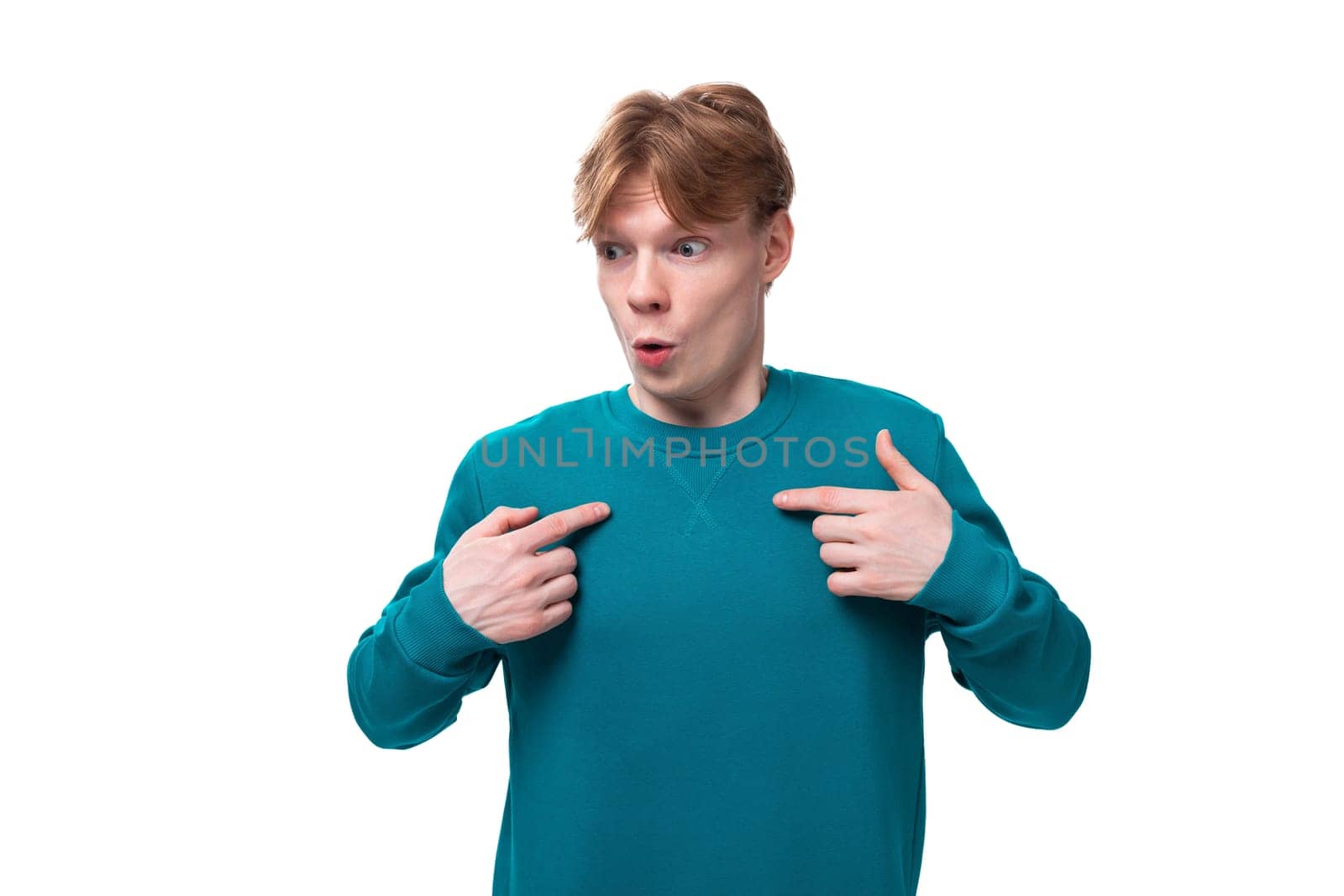 young surprised guy with short red hair dressed in a blue pullover on a white background by TRMK
