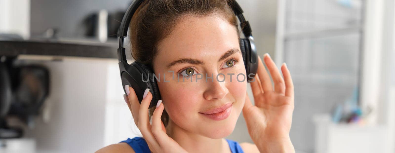 Face of beautiful woman in wireless headphones, enjoys sound, listens to music in wireless headphones by Benzoix