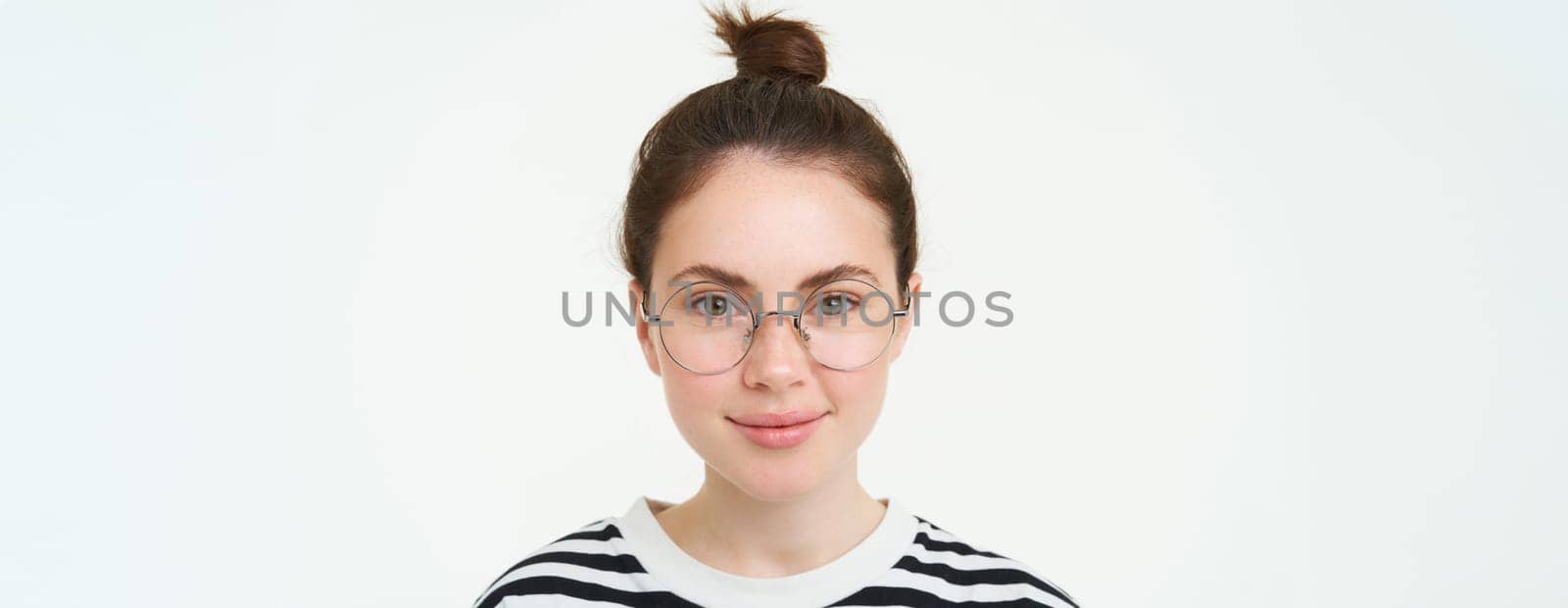 Portrait of beautiful young woman in glasses, wearing eyewear, smiling and looking happy, trying on new spectacles, standing over white background by Benzoix