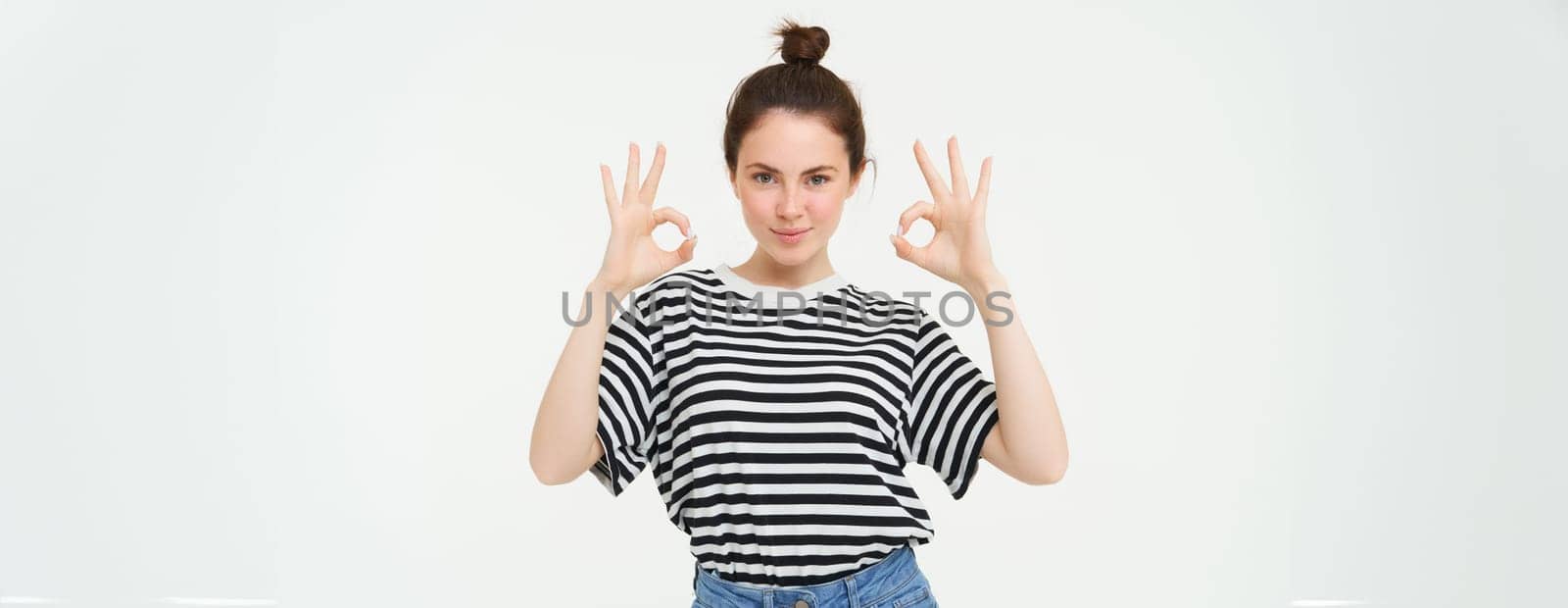 No problem, excellent choice. Smiling, confident young woman, showing okay, ok sign, zero gesture, recommends product, stands over white background.