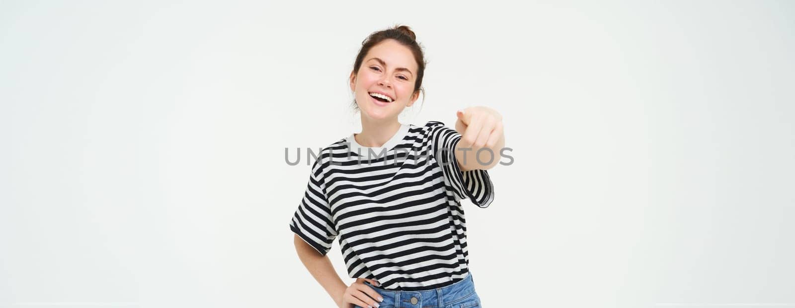 Image of stylish young woman, pointing finger at camera, inviting you, standing over white background by Benzoix