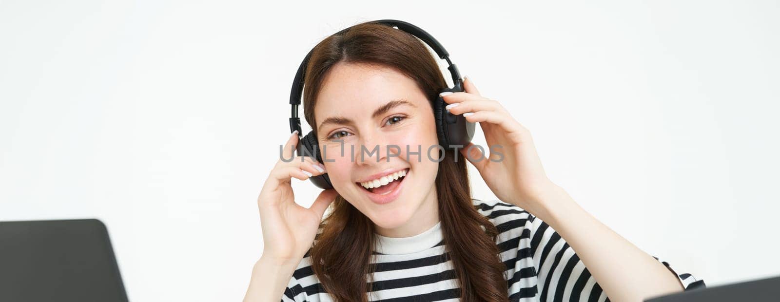Portrait of woman, smiling, wearing wireless headphones, listening music, studying in earphones, standing isolated over white background by Benzoix