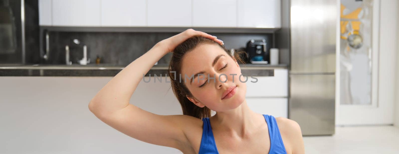 Close-up potrait of fitness woman, does training, workout from home, massaging neck, exercise in living room by Benzoix