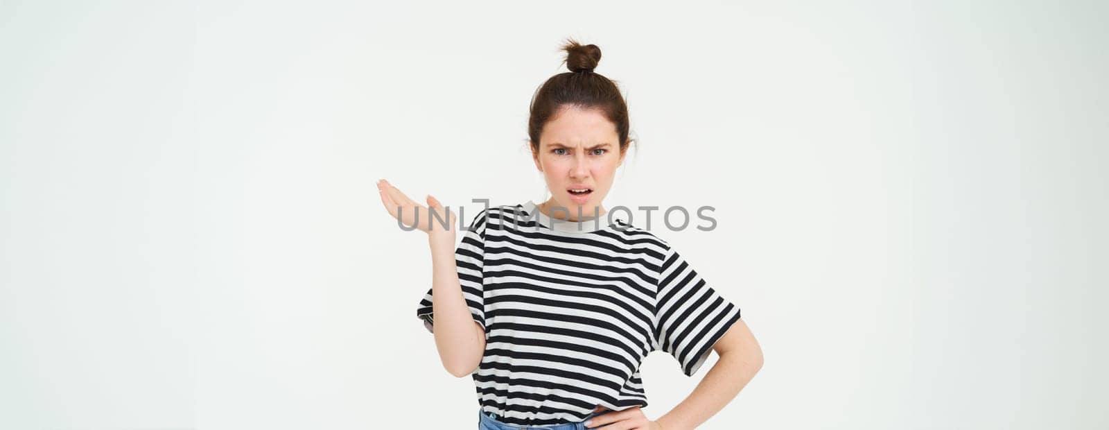 Portrait of angry woman complaining, raising one hand and shrugging looking frustrated, waiting for explanation, doesnt udnerstand smth, standing over white background.