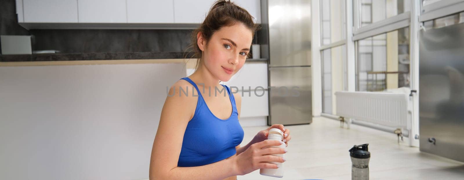 Image of strong and healthy sportswoman doing workout at home, taking pills, vitamins or dietary supplements after fitness training, Health and medication concept