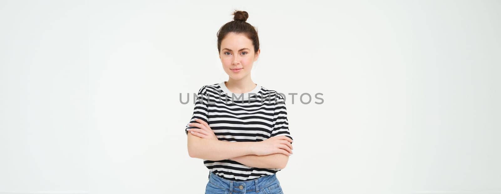 Portrait of young stylish woman, 25 years old, looking upbeat and motivated, posing for photo against white background.