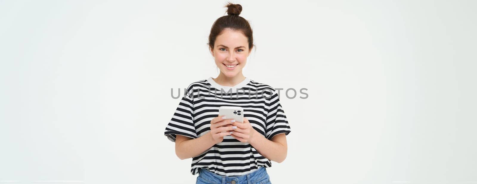 Technology and people concept. Young woman with mobile phone, smiling, using smartphone app, social media application, isolated over white background by Benzoix