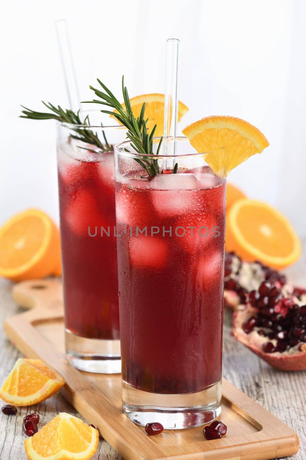 Pomegranate orange holiday punch with ice and rosemary. This is a sweet, tart and refreshing cocktail perfect for celebrating any party.
