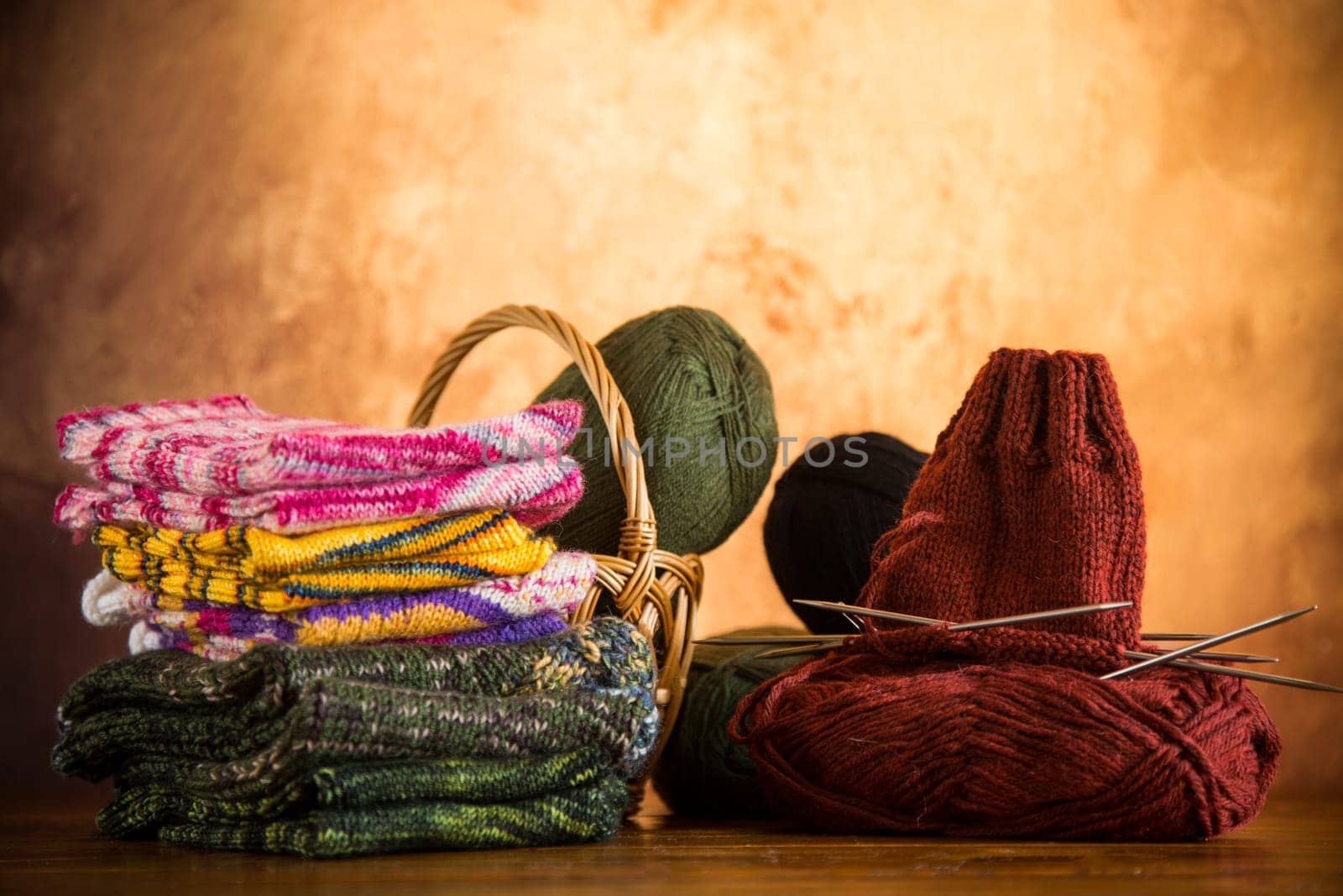 Colored yarn, knitting needles and other items for hand knitting on a dark wooden table.