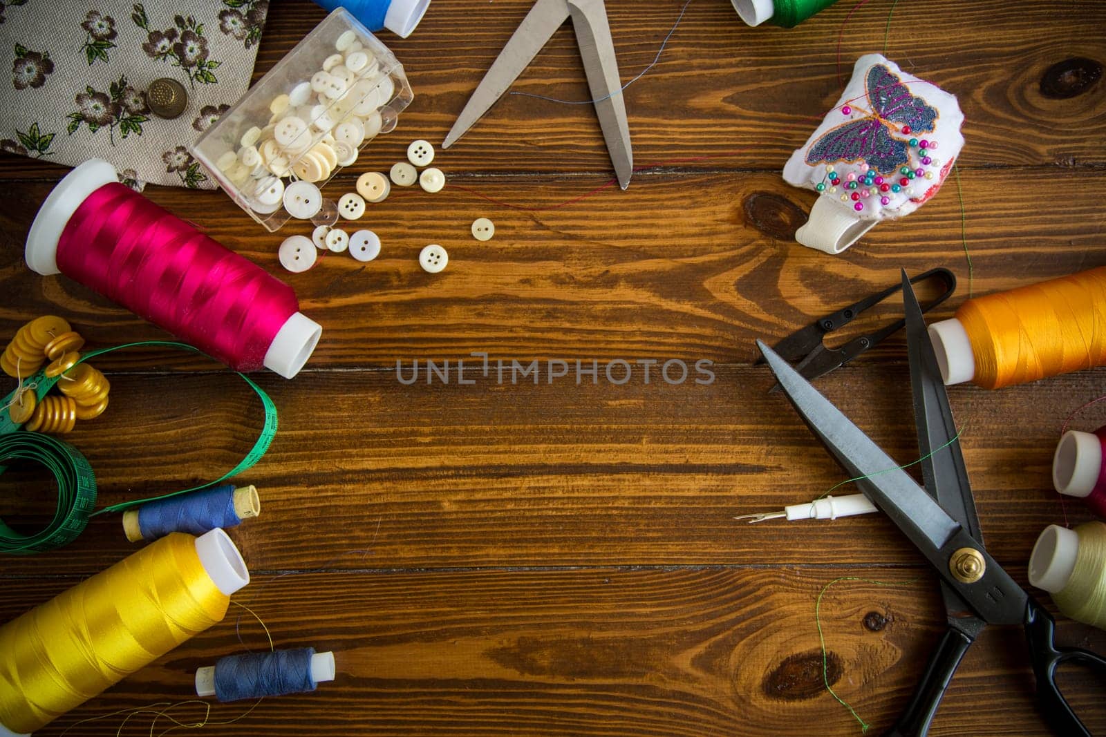 Sewing accessories and fabric on a wooden background. Sewing threads, needles, pins, fabric, buttons and sewing centimeter. Top view, flat lay. High quality photo