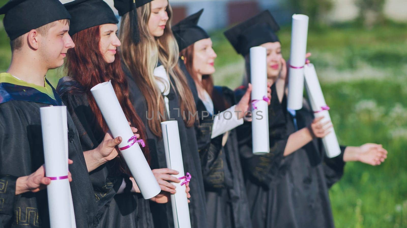 Scrolls of diplomas in the hands of a group of graduates. by DovidPro