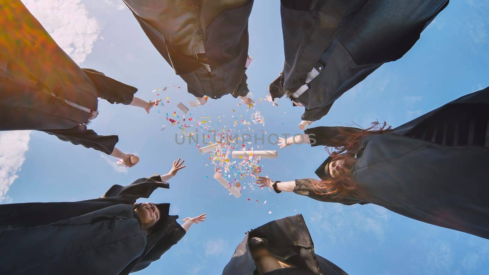 College graduates toss diplomas with confetti up in the air