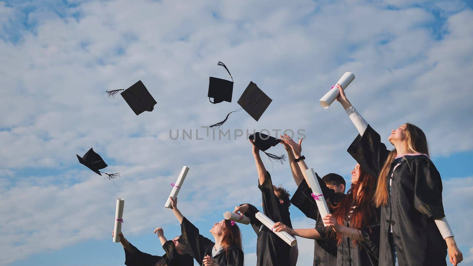 Graduating students hands throwing graduation caps in the air