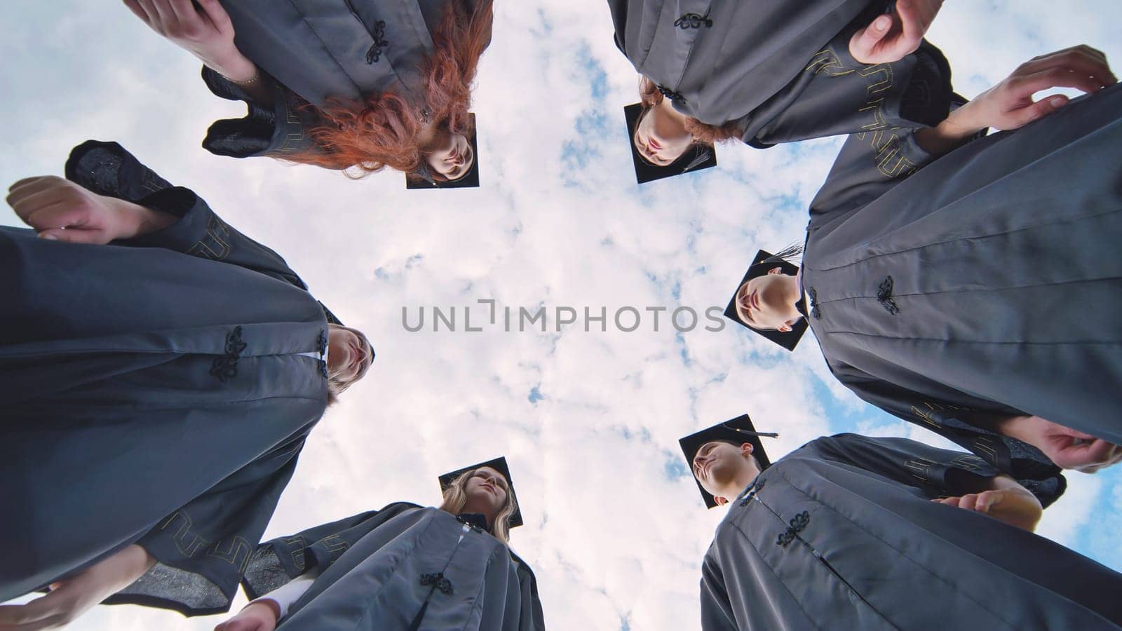 Graduates in black robes stand in a circle