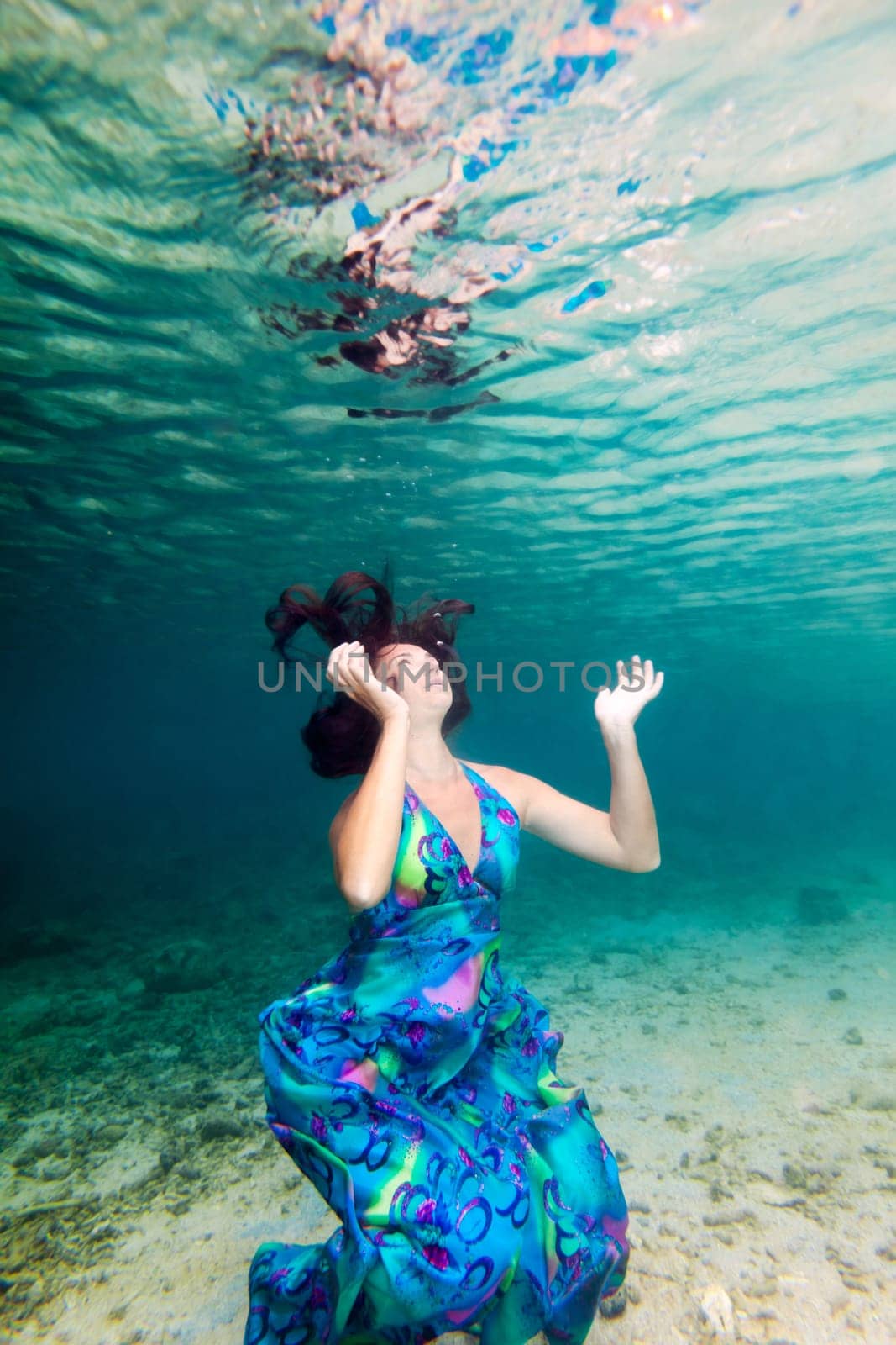 Young beautiful woman in blue dress underwater