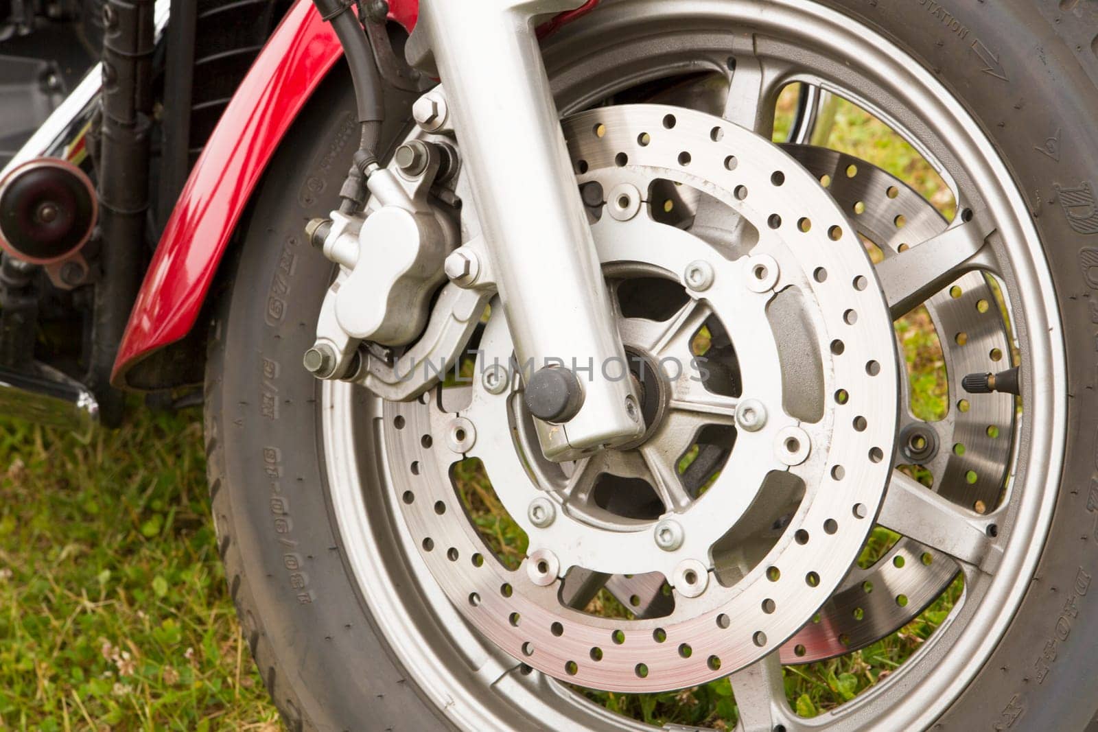 Bike chromed wheel on grassy background seems used
