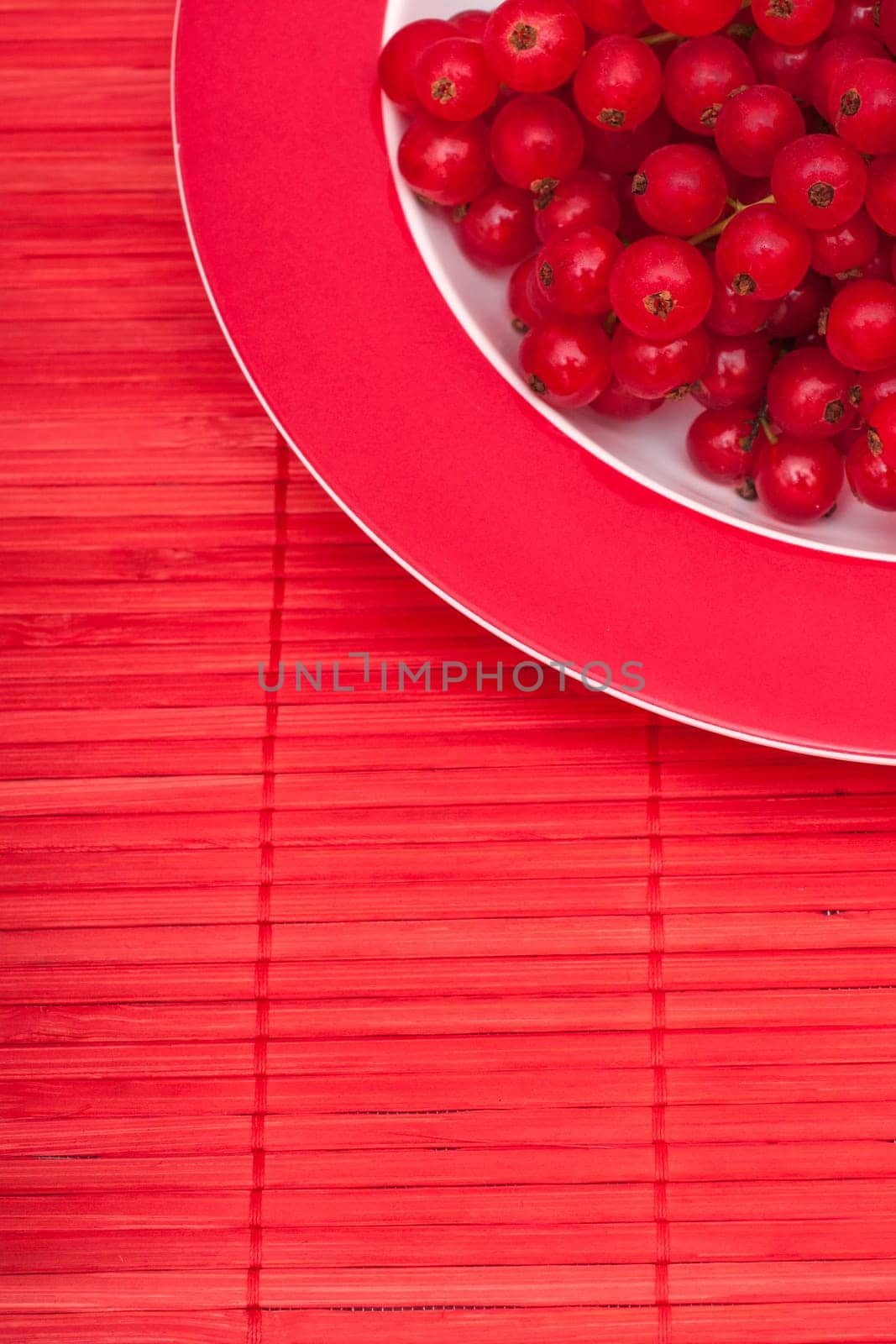 Red currants in a plate on a red blanket