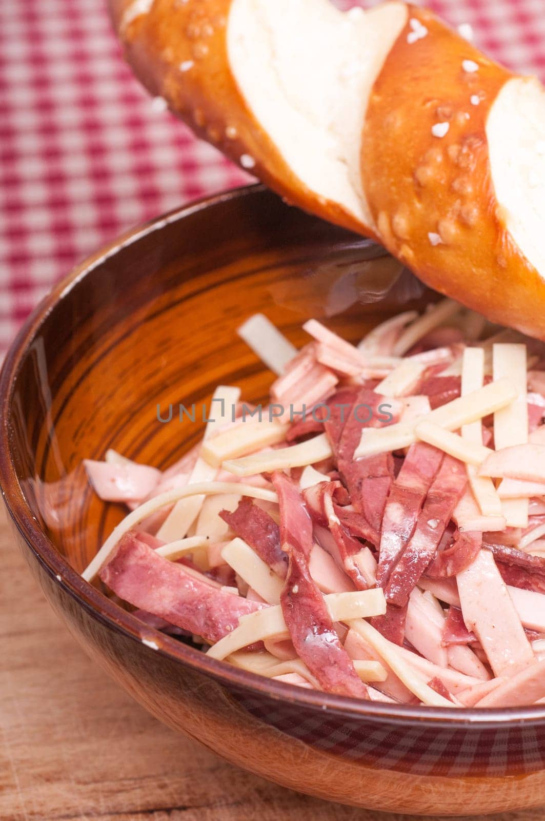 Sausage salad and pretzel stick on a checkered tablecloth