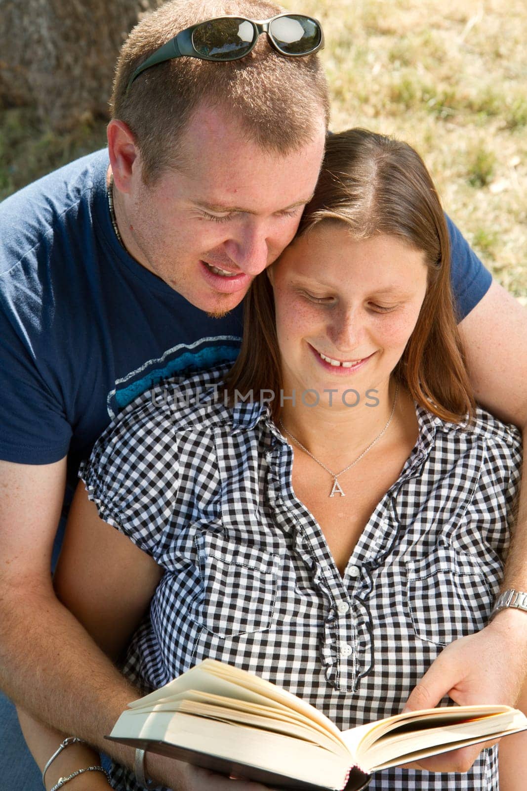 A boyfriend and girlfriend reading a book in a park