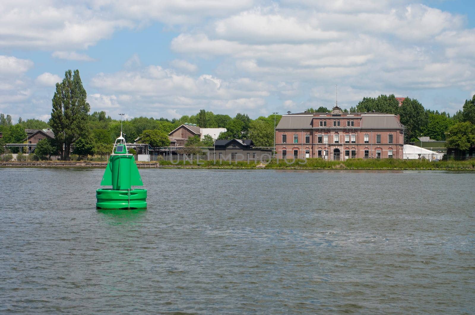 Green navigational buoy with solar panel in the Dutch North Sea Canal