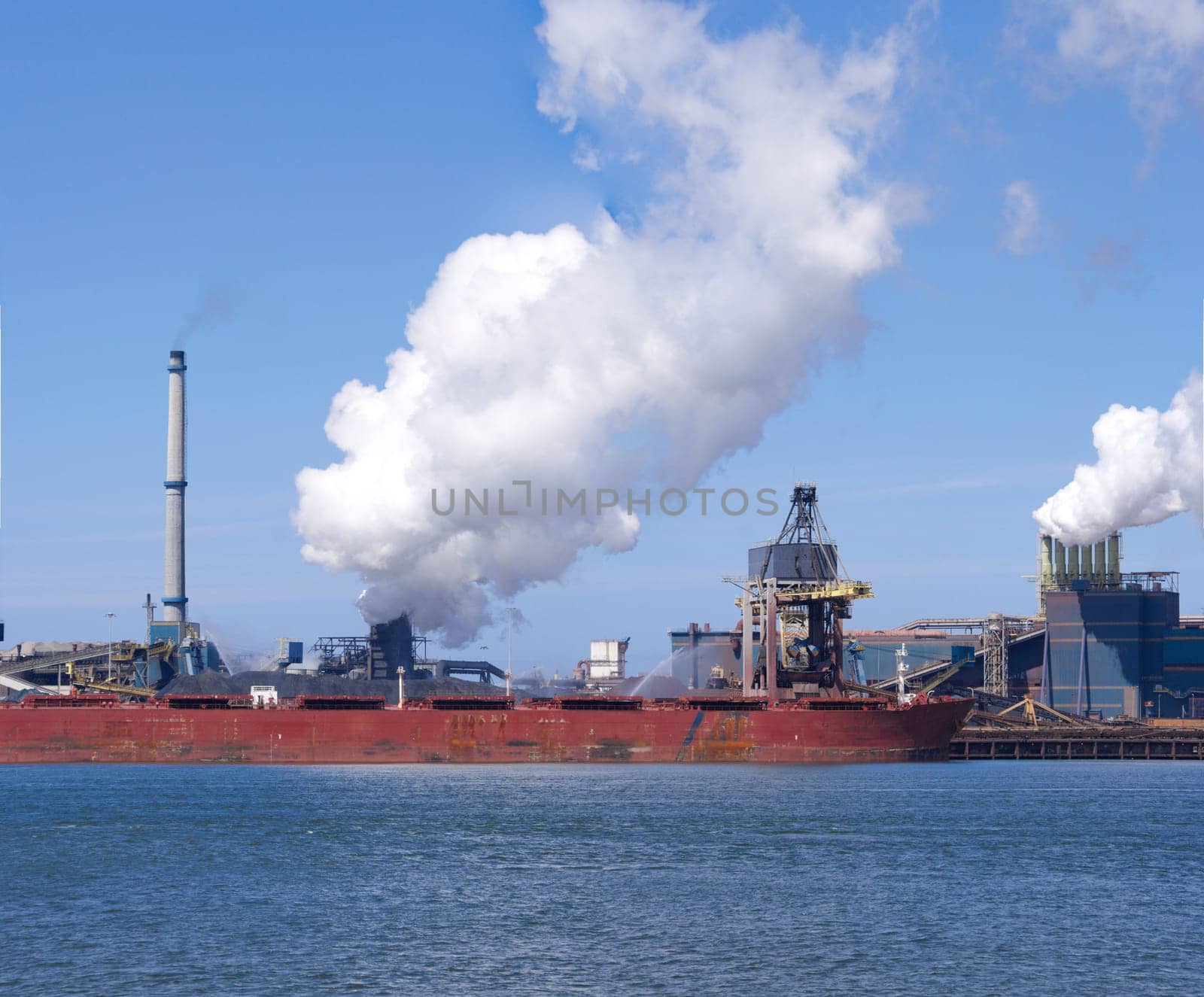 ship unloading in front of a large steel factory in IJmuiden, Netherlands