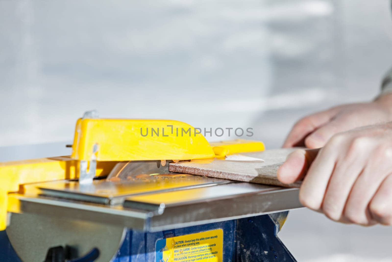 A person cutting a tile using a wet saw blade