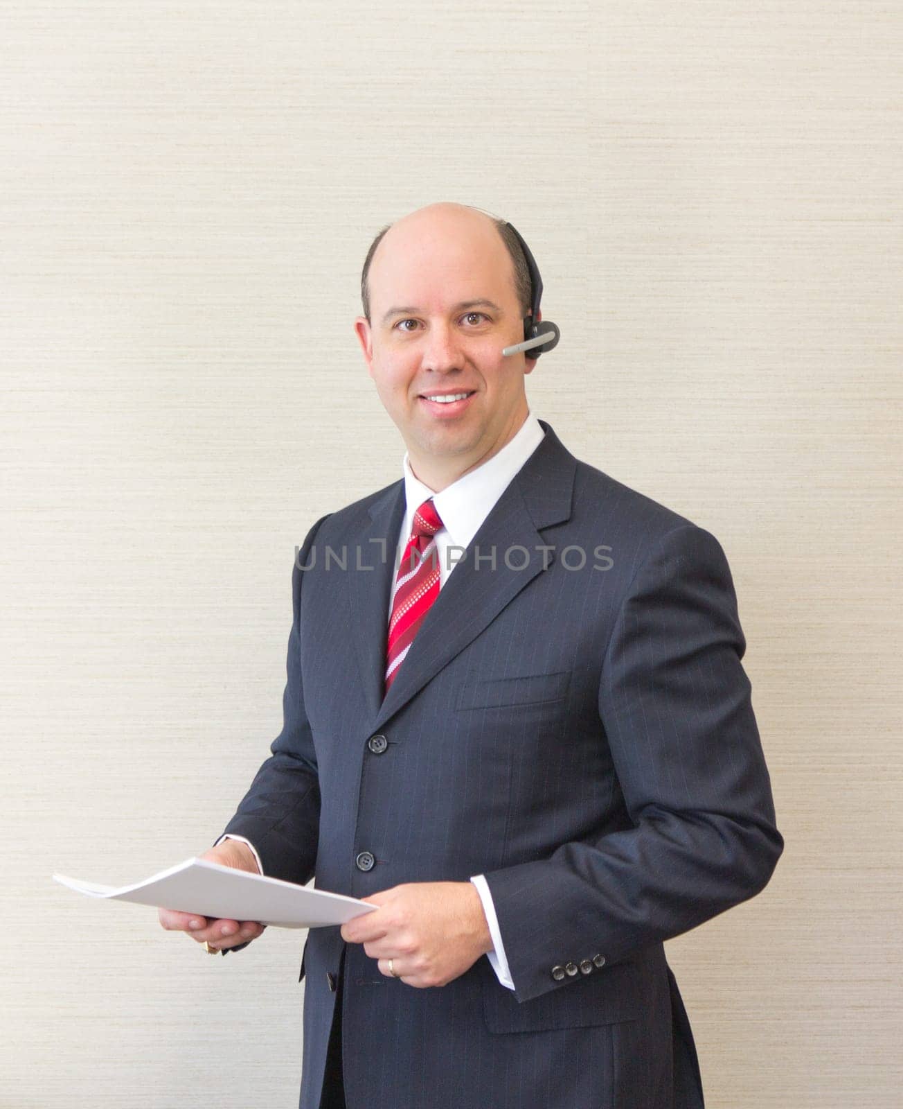 Business man with a handsfree telephone headset holding a document.