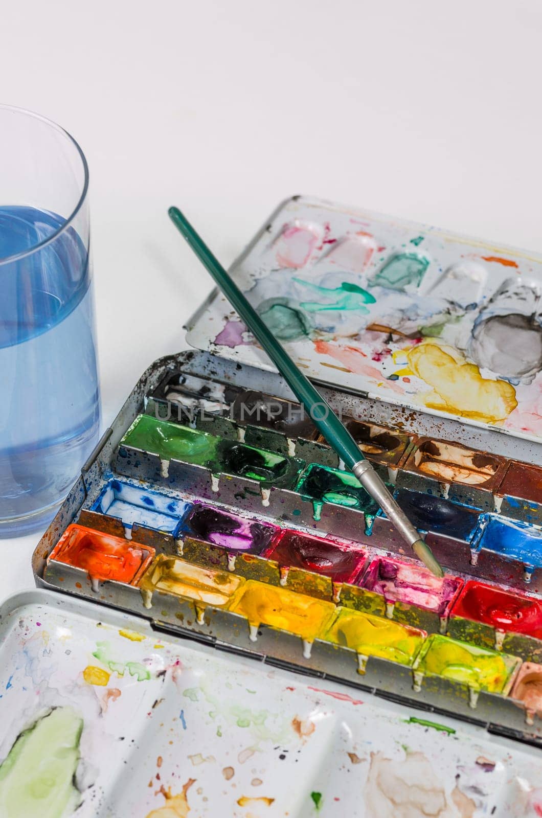Watercolor paint box with brush and water glass