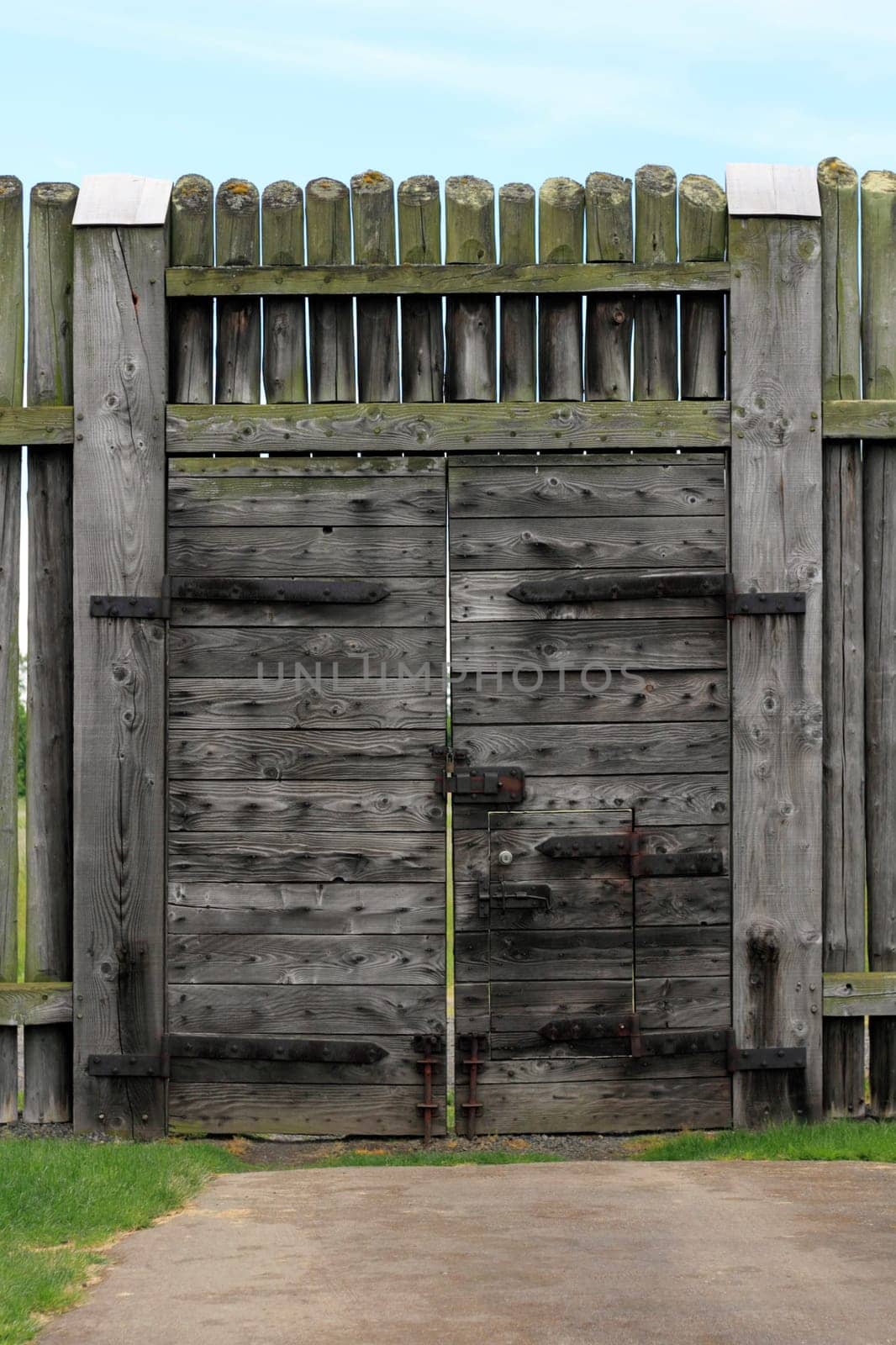 Very large historic gate a few hundred years old and standing at least 10 feet tall under a partly sunny sky.