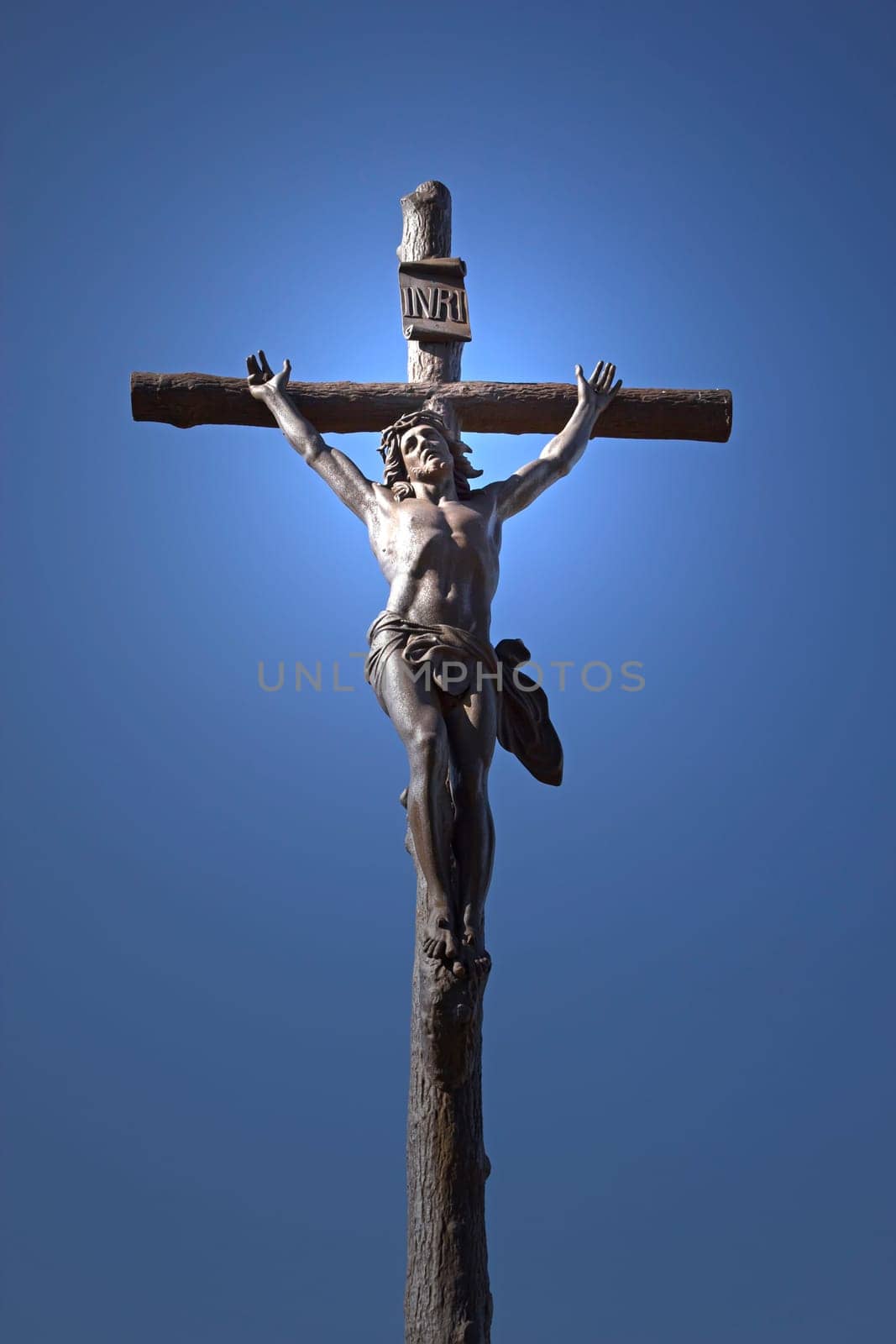 Statue of Jesus Christ on a cross. Blue sky in the background. Vertically.