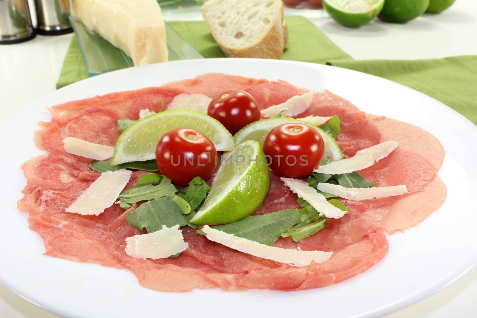 a plate of carpaccio with parmesan,lime and arugula
