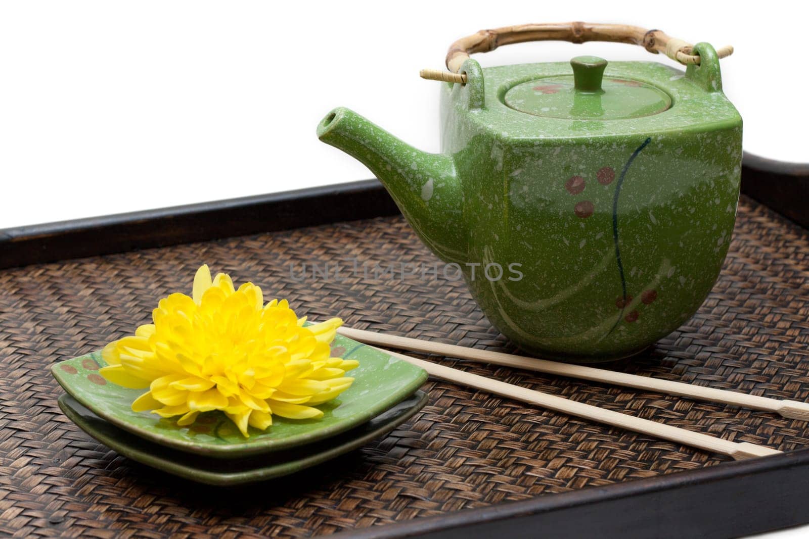 Bamboo tray, green ceramic teapot, saucer, yellow chrysanthemum and chopstick on white background