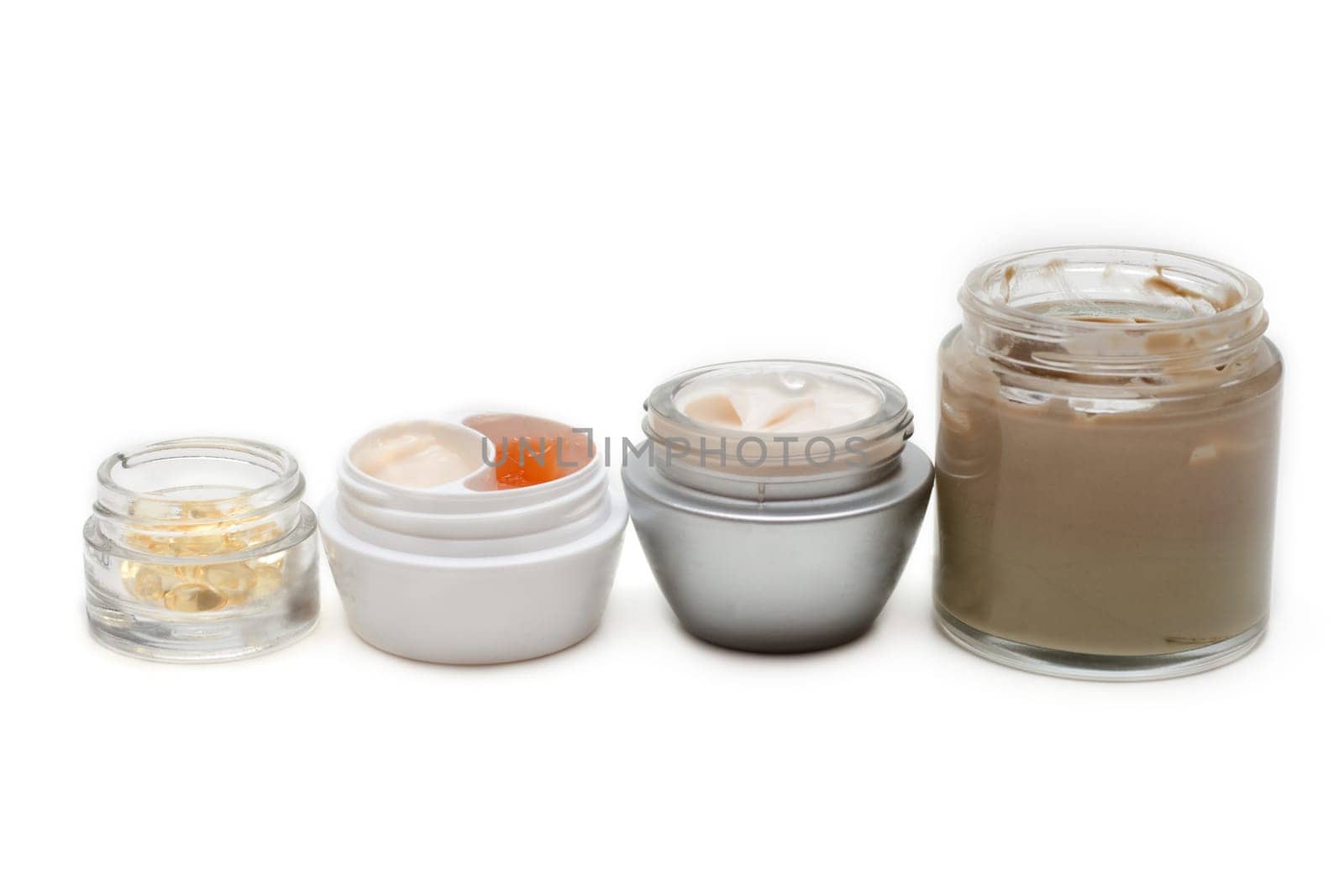 Opened banks with make-up cream on white background
