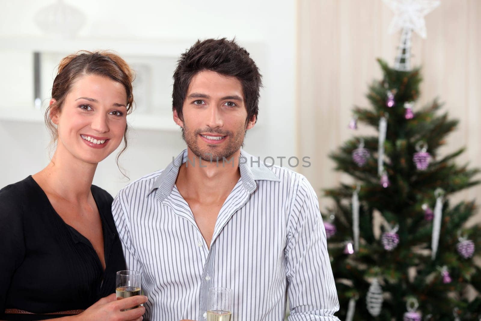 Couple posing in front of their Christmas tree