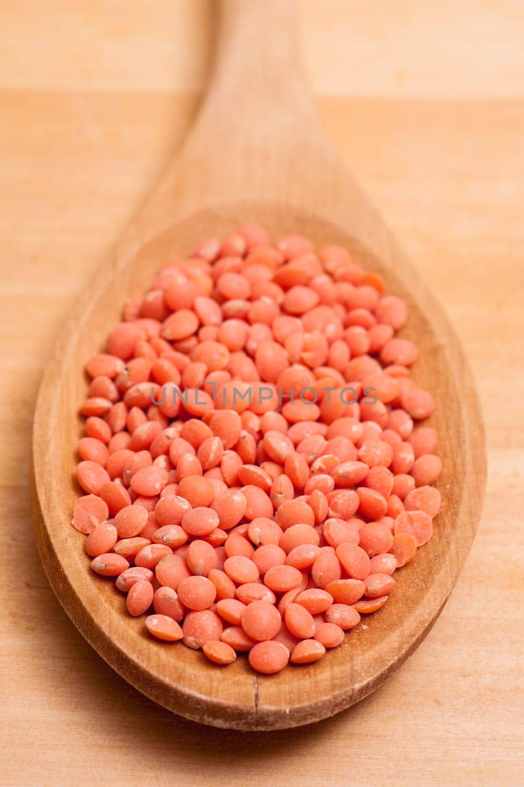 Close-up of red lentils on a wooden spoon