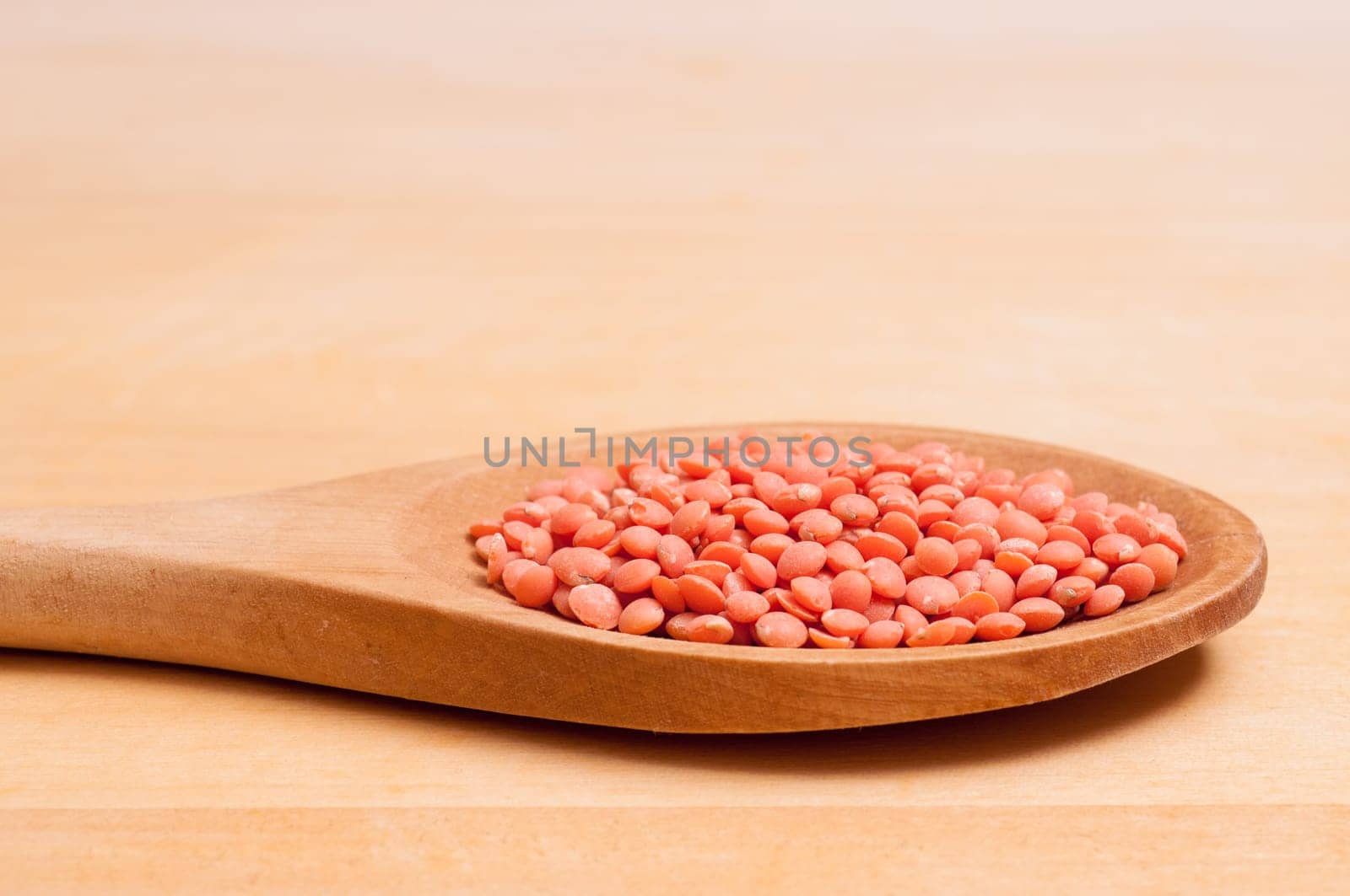 Close-up of red lentils on a wooden spoon