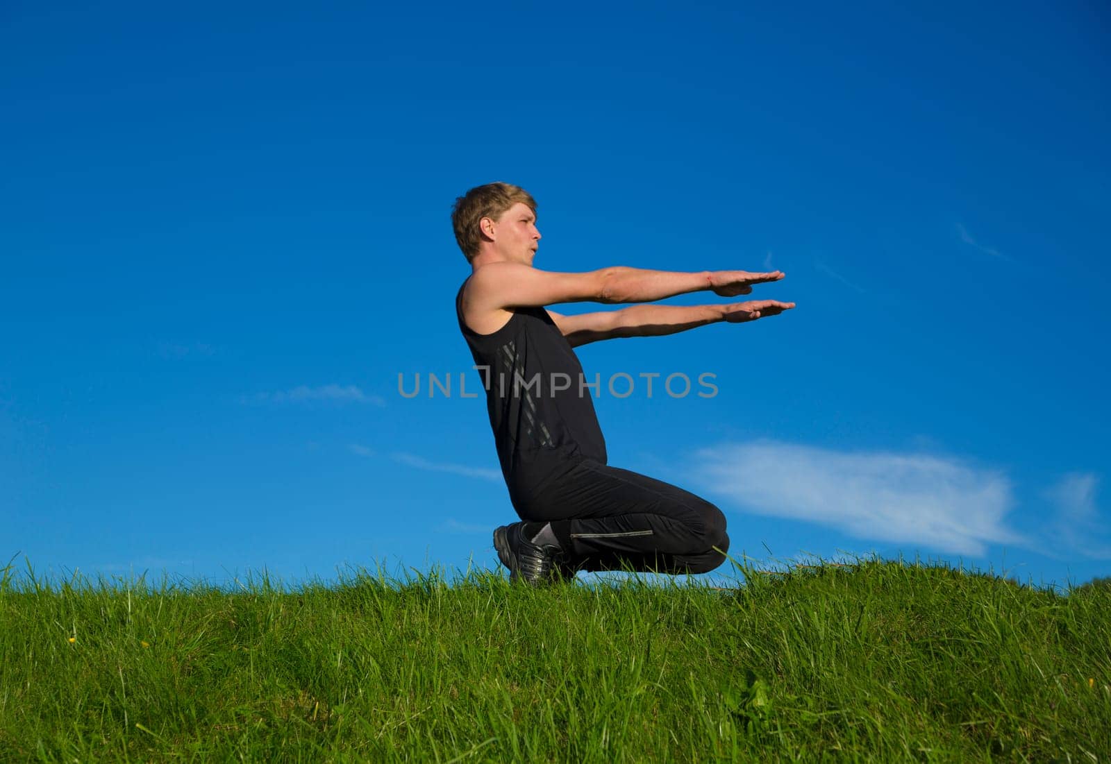 Sportsman is squatting on top of green hill
