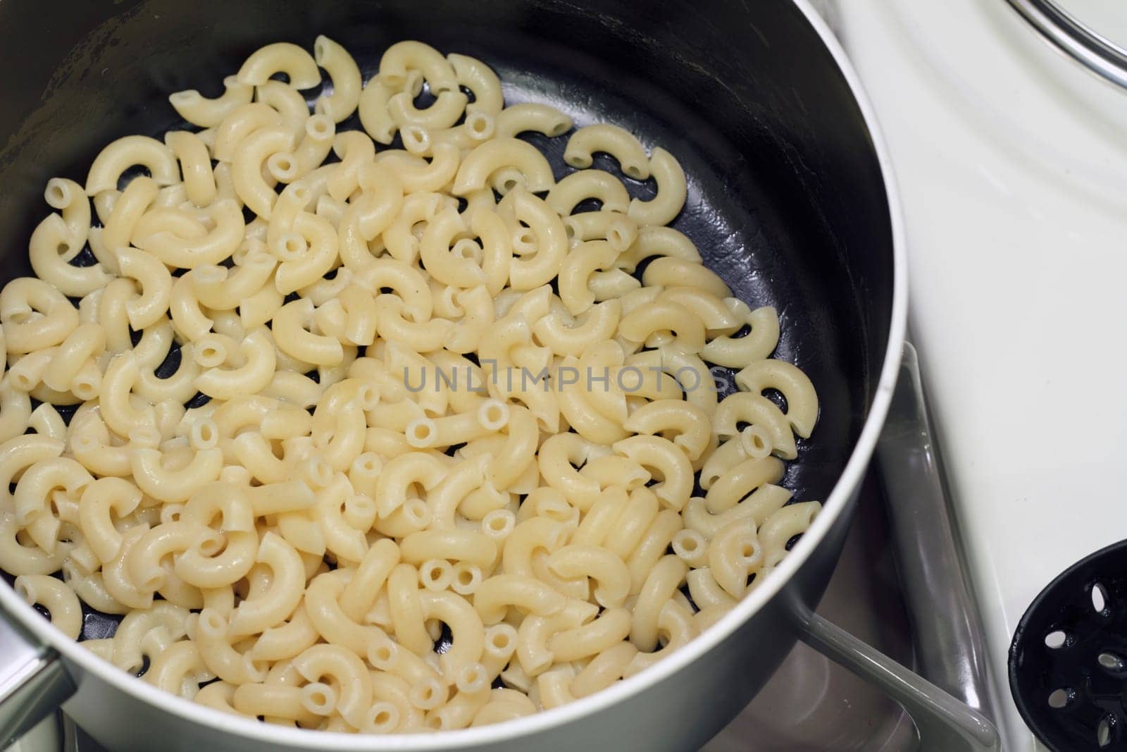 Finished pasta in a pan on the stove ready to add ingredients to.