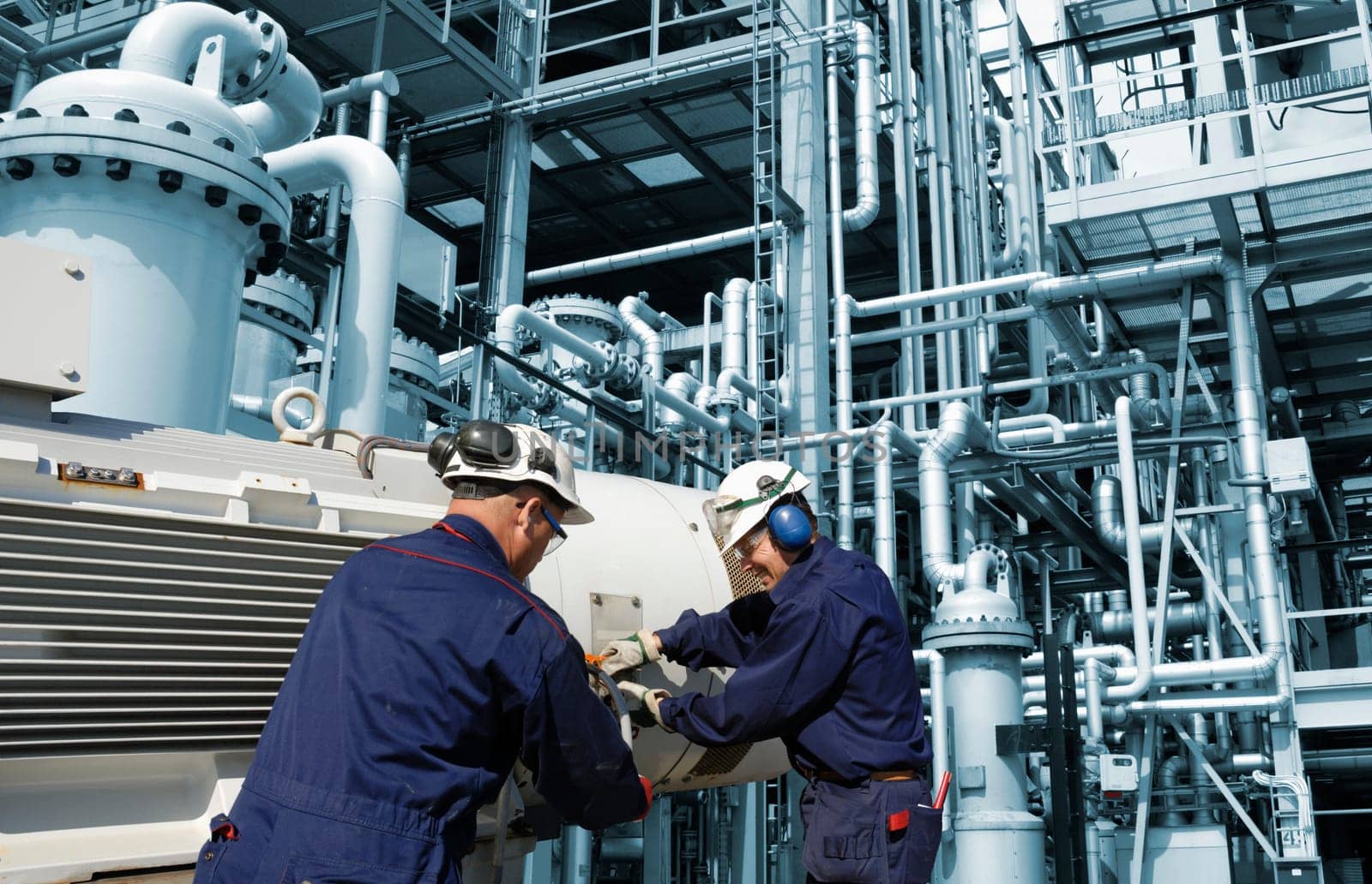 two oil and gas engineers, workers, inside refinery with pipelines