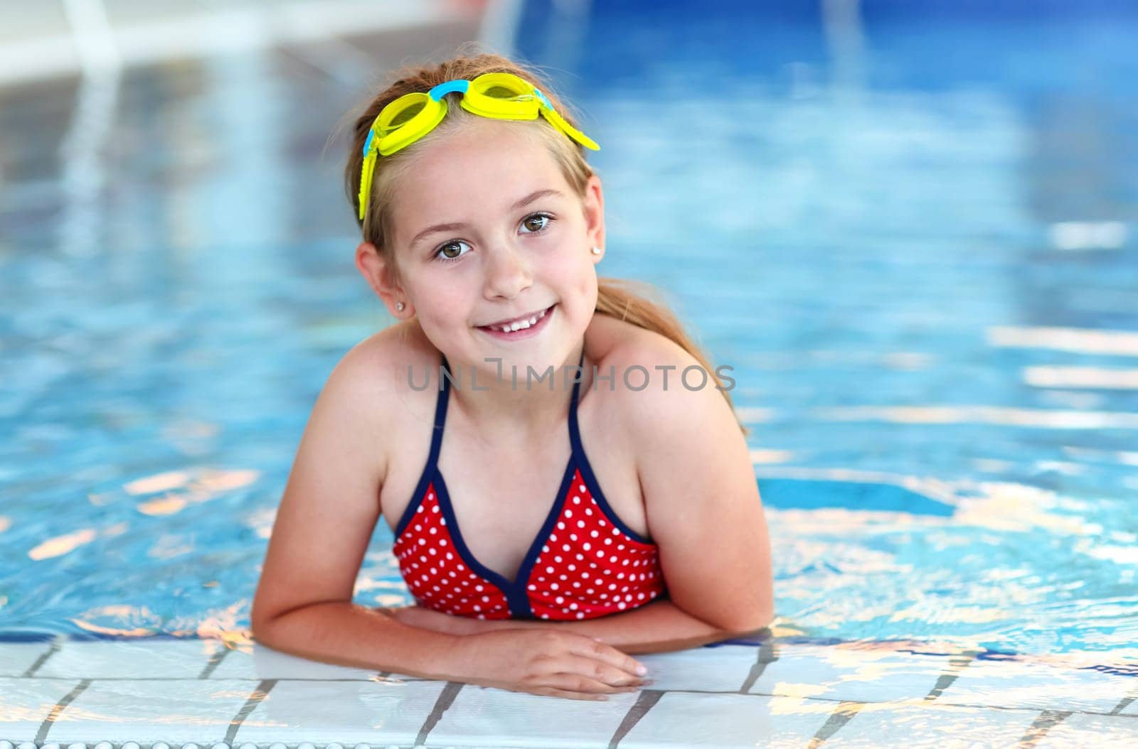 Cute girl with goggles in swimming pool