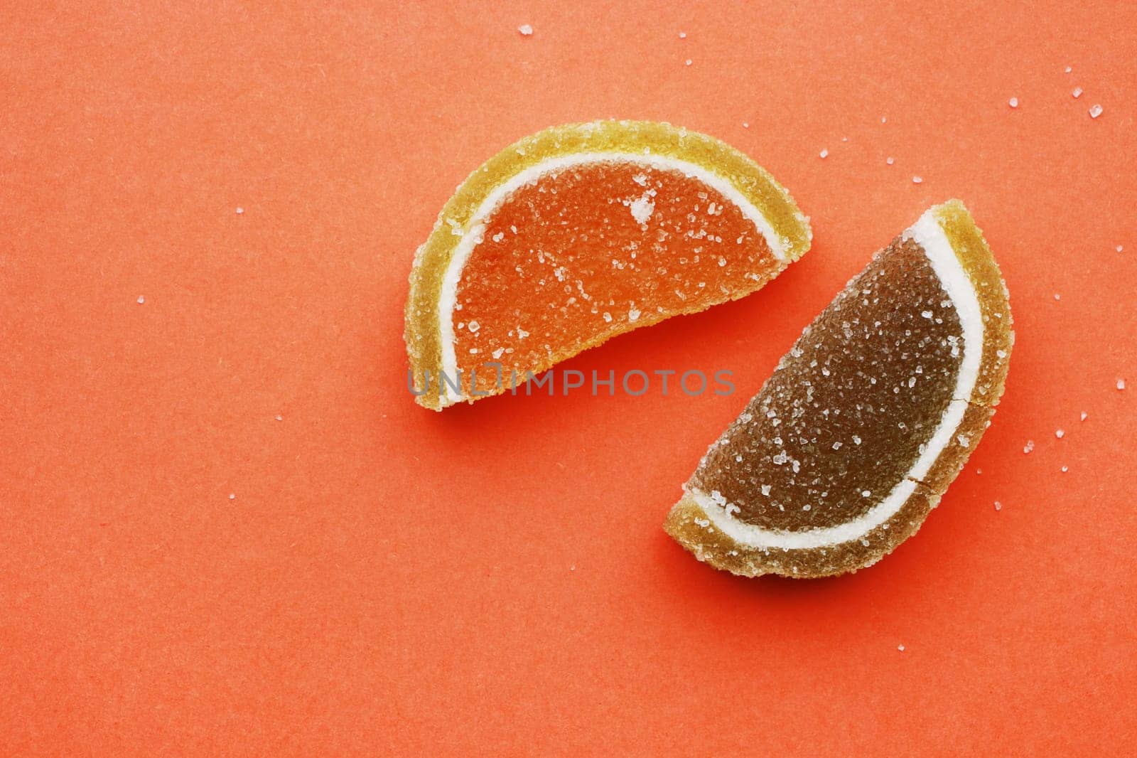 Two semicircular marmalade slices lie on a red background, top view.
