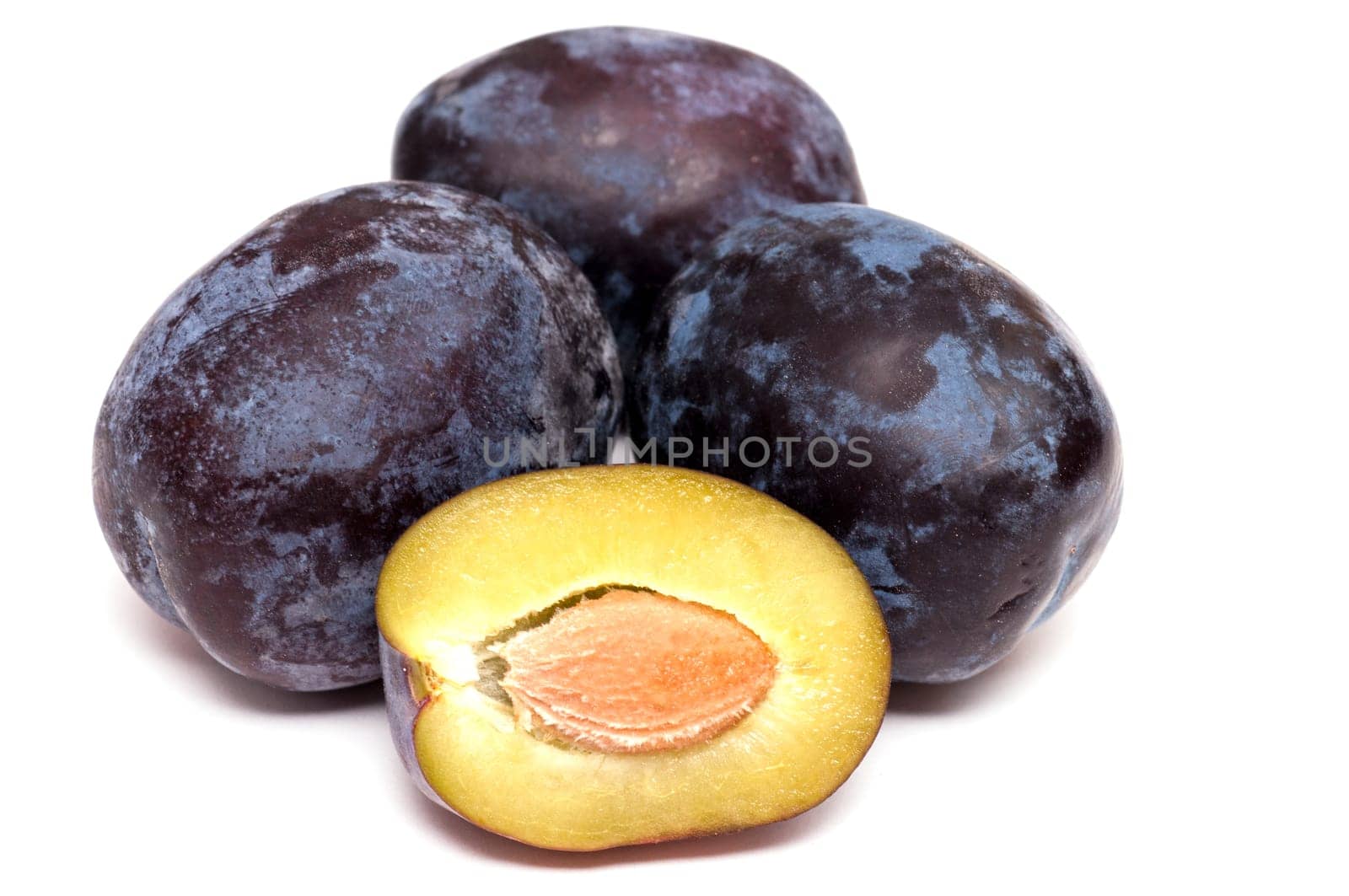 Plums and plum pit on white background