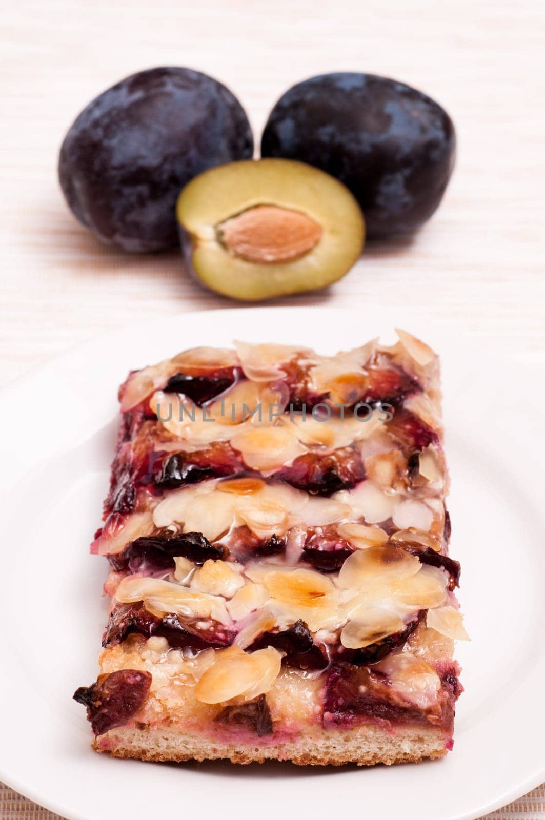 Plum cake on a plate and plums in the background