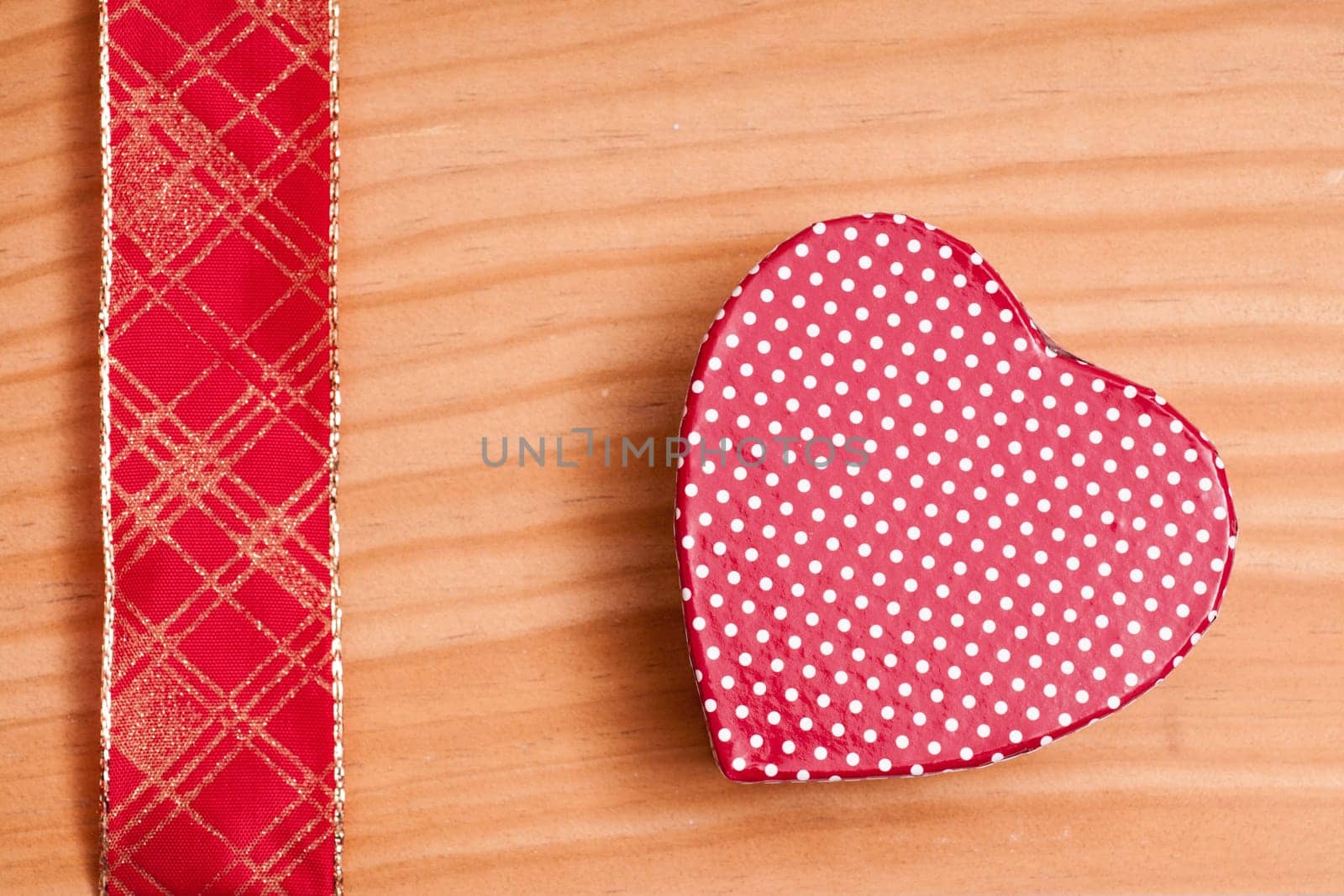 Red heart and gold-red ribbon on a wooden board