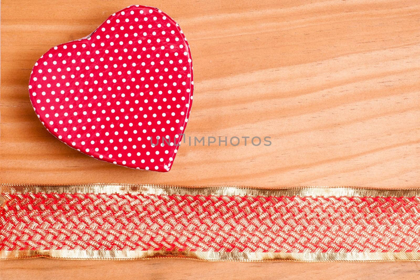 Red heart and gold red ribbon on a board