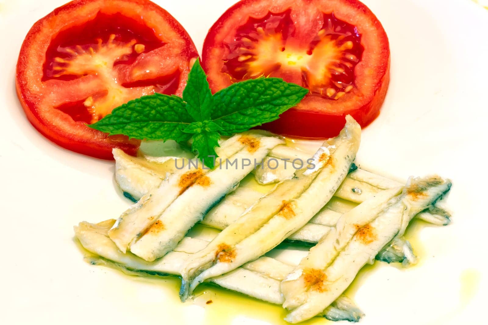 ration of anchovies in vinegar, garnished with tomato and mint