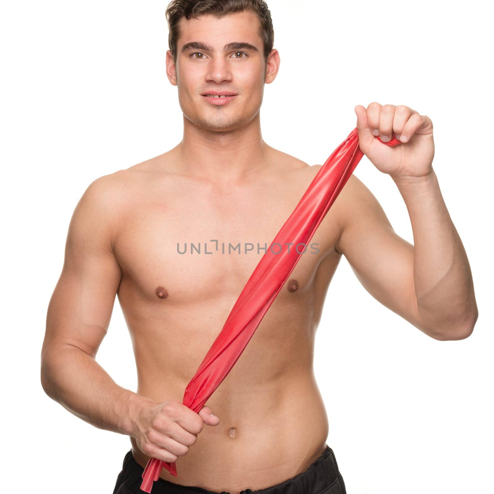 Young man with a red gymnastics band against a white studio background