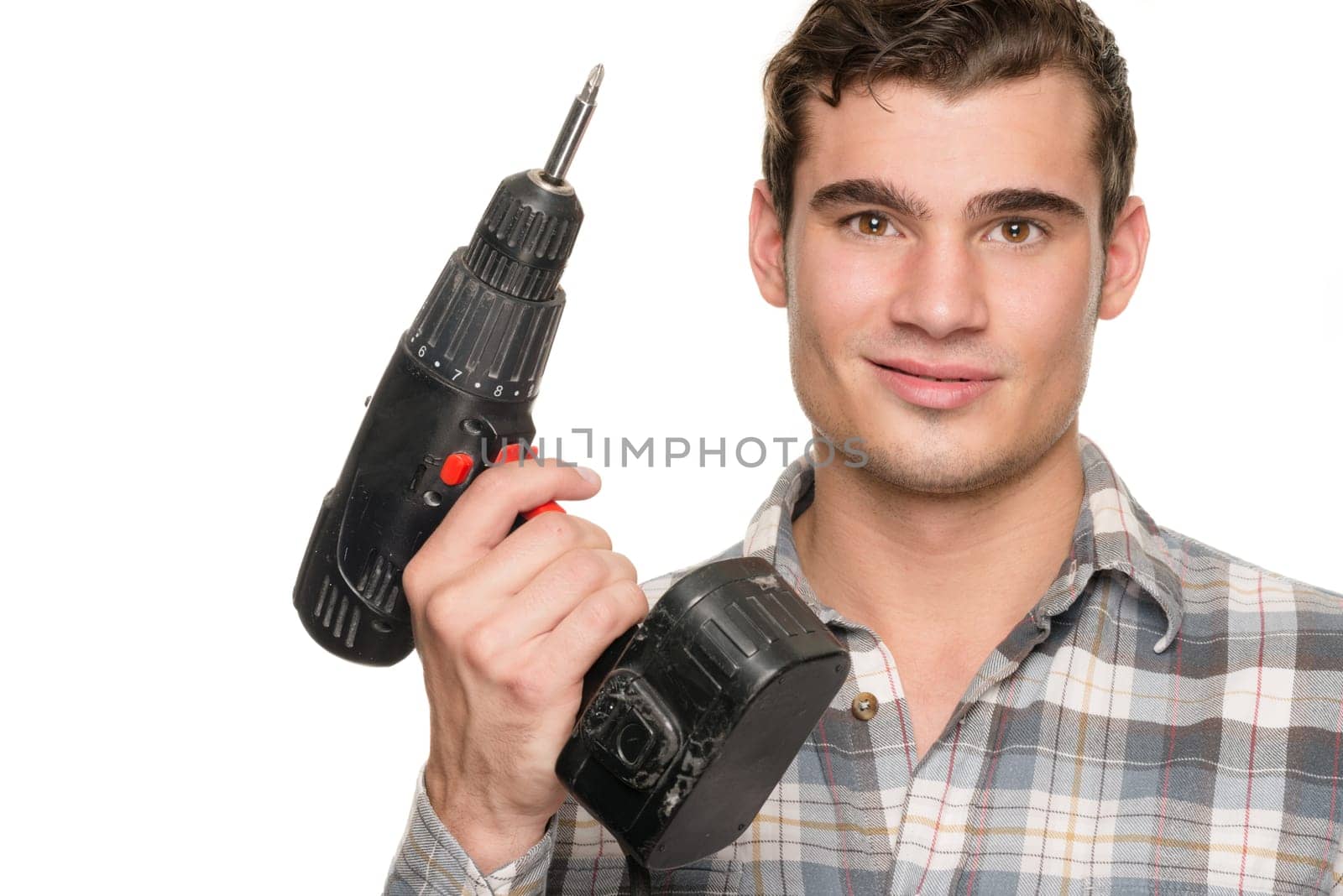 Young man with cordless screwdriver in front of white studio background