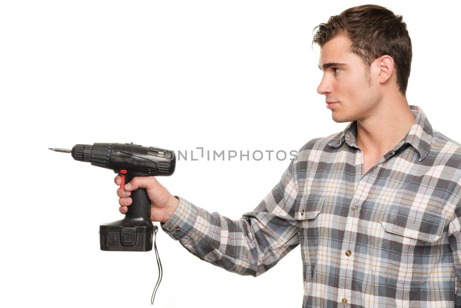 Young man with cordless screwdriver in front of white studio background